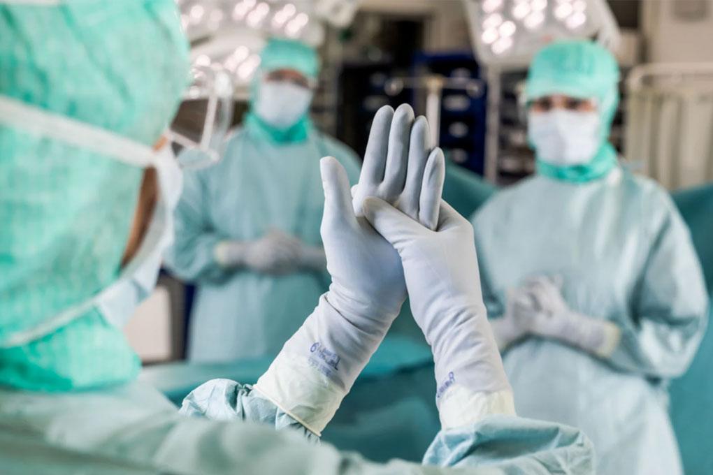 Personnel mettant des gants chirurgicaux à l'intérieur d'un bloc opératoire